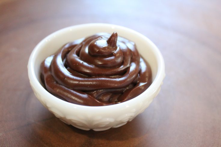 dairy free chocolate pudding in a white dip bowl sitting on a wooden surface