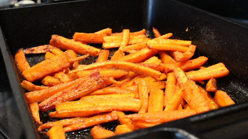 Seasoned roasted carrots in a 9x13 cast iron pan