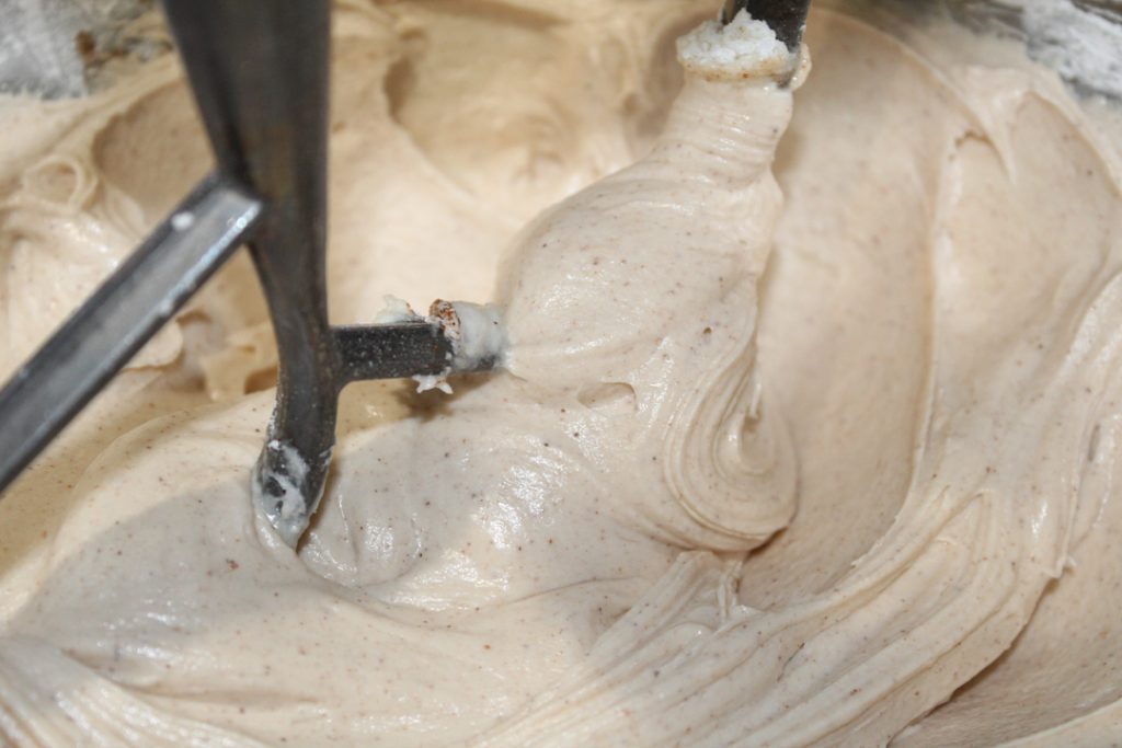 cinnamon buttercream frosting in a stainless steal mixing bowl with a paddle attachment.