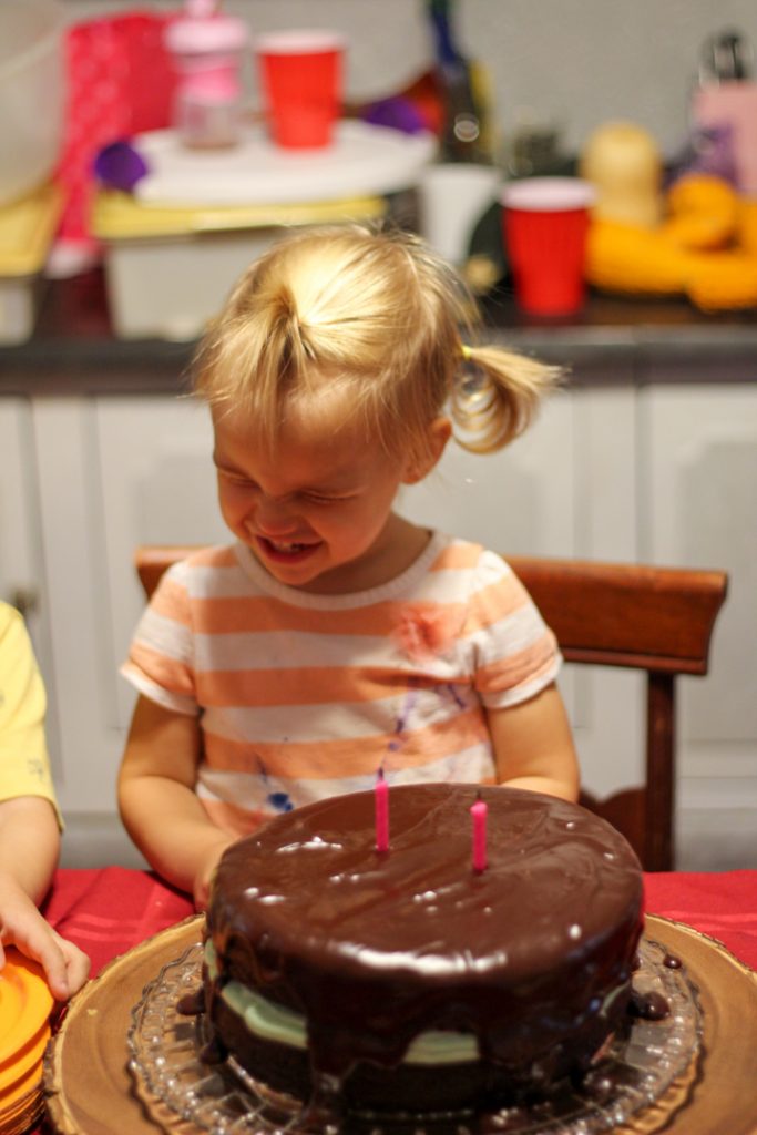 Little girl smiling with her eyes closed after blowing out the candles on her birthday cake.