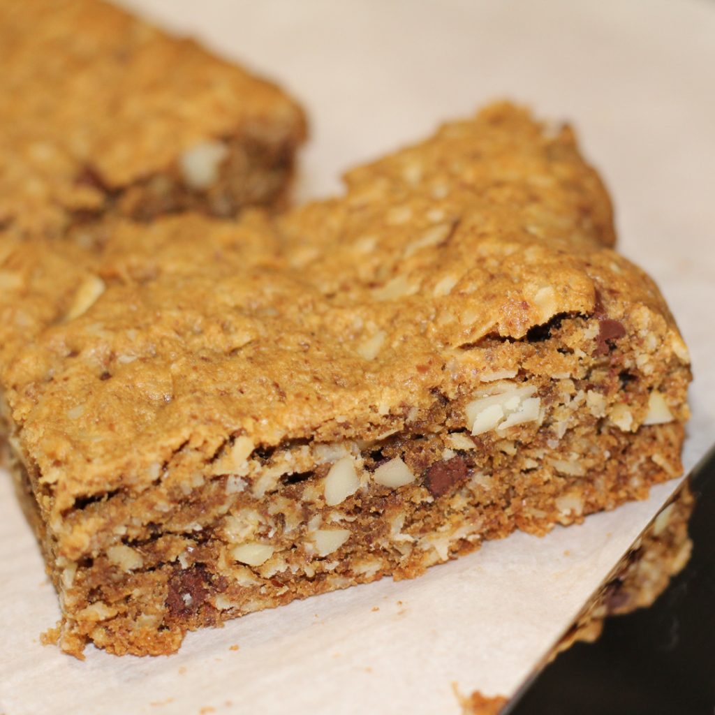 close up of one gluten free lactation snack bar. You can see the almond slivers, chocolate chips, and other ingredients from the side. 