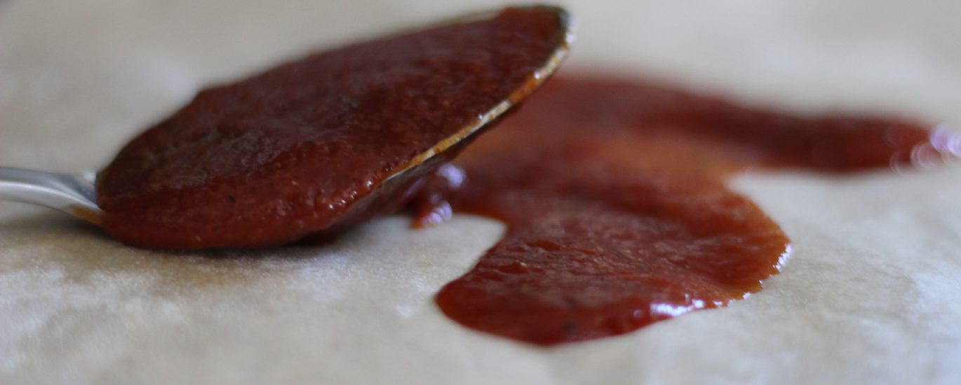 homemade bbq sauce on a spoon with some spread on brown parchment paper